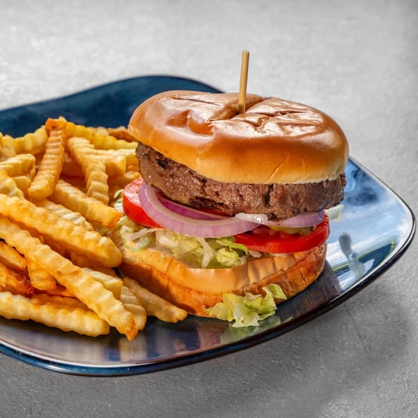 A Tampa Joe's burger with lettuce, tomato, and onion, served with crinkle-cut fries on a blue plate.
